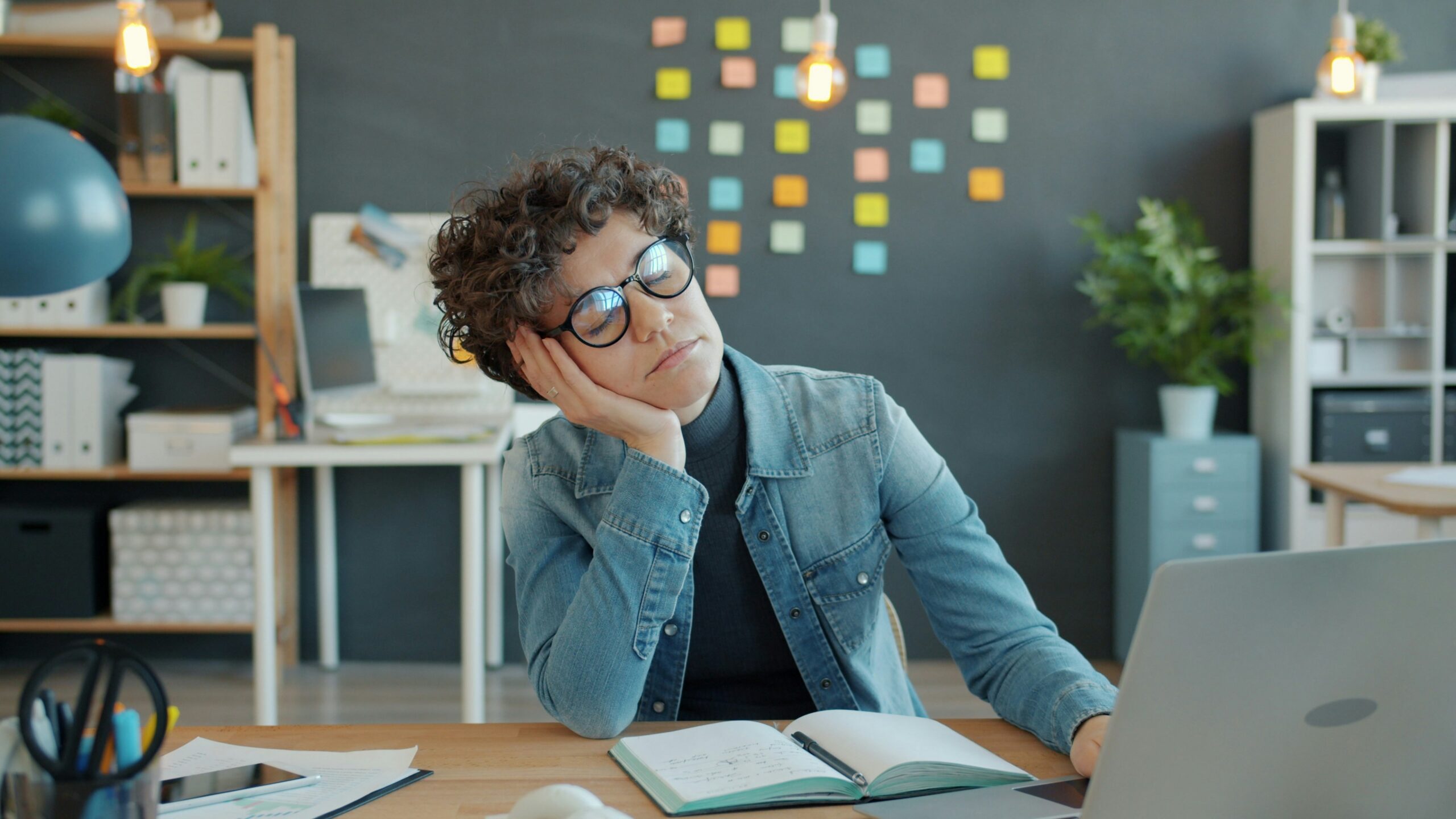Woman at computer with closed eyes, experiencing nonprofit burnout