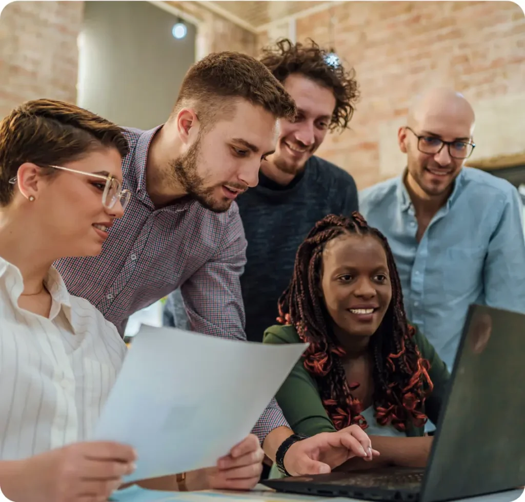 group of colleagues gathers around a laptop