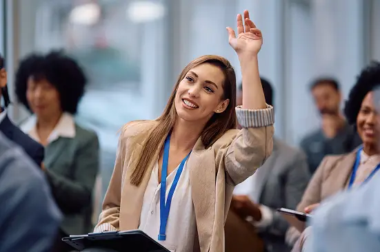 woman raises her hand at a conference