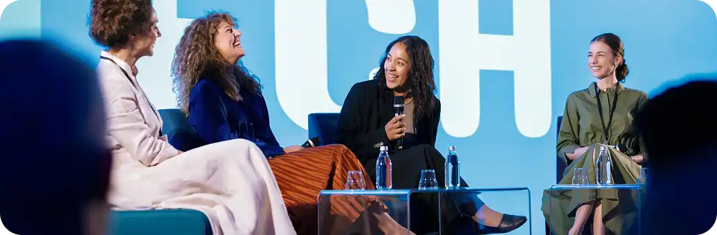 women laugh during a conference panel discussion